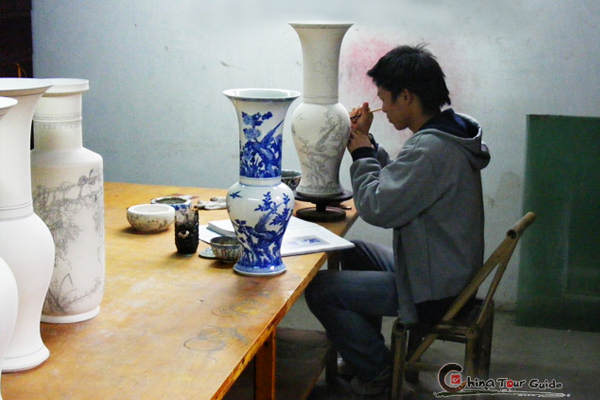 The worker is focusing on the hand-painting on the porcelains